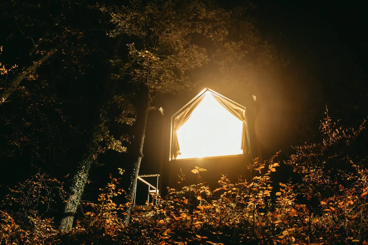 Glamping, das in der Dämmerung im Herbstwald leuchtet