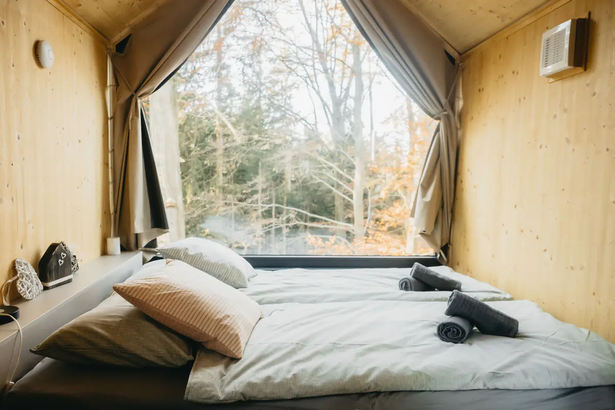 Bett am großen Fenster mit Blick in den Wald